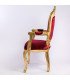 Side view of the baroque-style chair in gold and red, with a carved wooden frame and red velvet upholstery in a white setting.