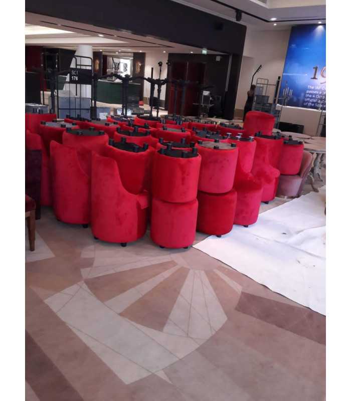 Red velvet barrel chairs and poufs grouped before setup in a reception hall, delivered by 126 Events