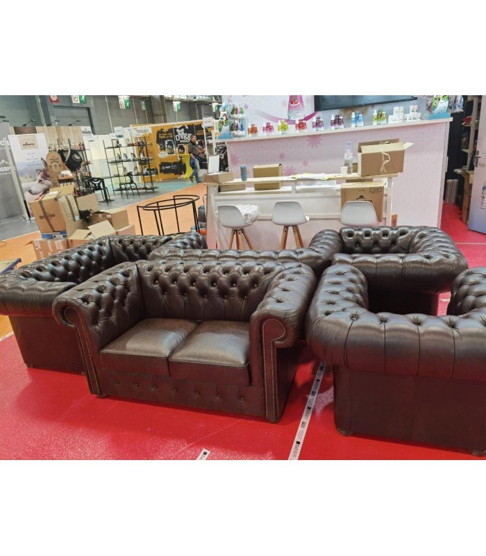 Three brown leather Chesterfield sofas and two matching armchairs in an event lounge area.