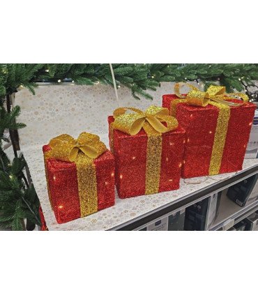 Set de 3 boîtes cadeaux LED disposées sur une table lors d’une décoration de Noël avec sapin en arrière-plan.