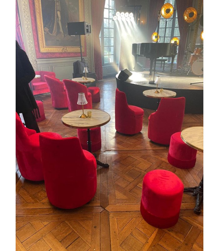 Red barrel chairs facing a stage with a piano in a castle reception room, event furniture rental in Paris