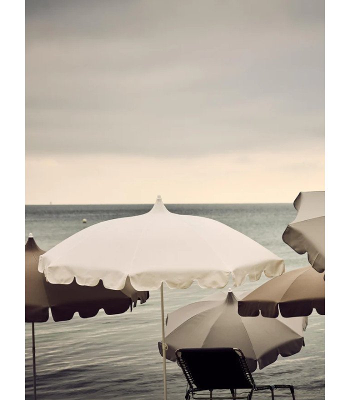 White parasol with frills on a beach