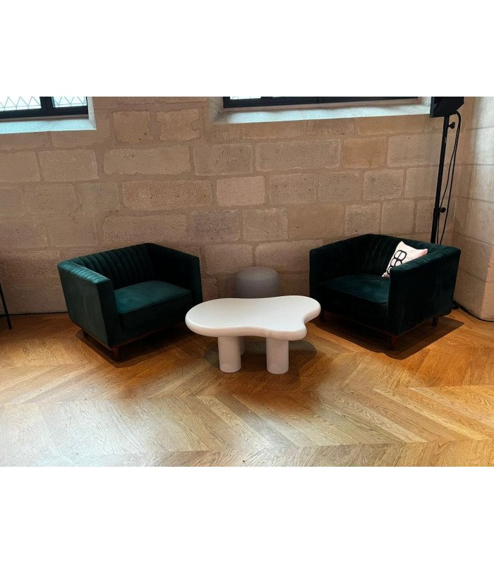 Table basse forme nuage ivoire à 4 pieds dans un espace lounge avec canapé noir pour événement