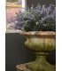 Coupe Médicis en pierre avec composition florale placée près d’une fenêtre