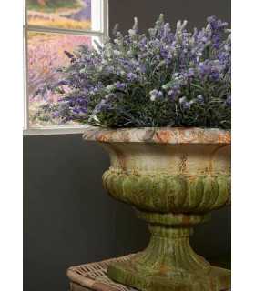 Coupe Médicis en pierre avec composition florale placée près d’une fenêtre