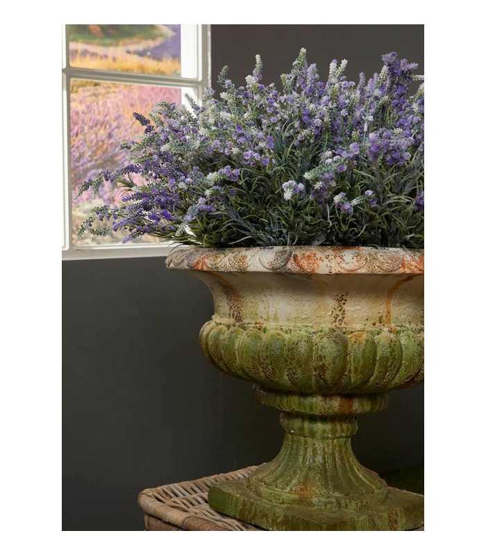 Coupe Médicis en pierre avec composition florale placée près d’une fenêtre