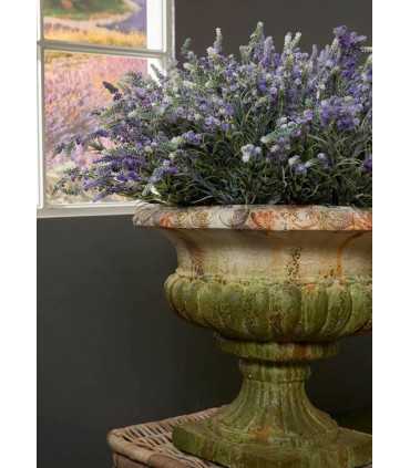 Coupe Médicis en pierre avec composition florale placée près d’une fenêtre