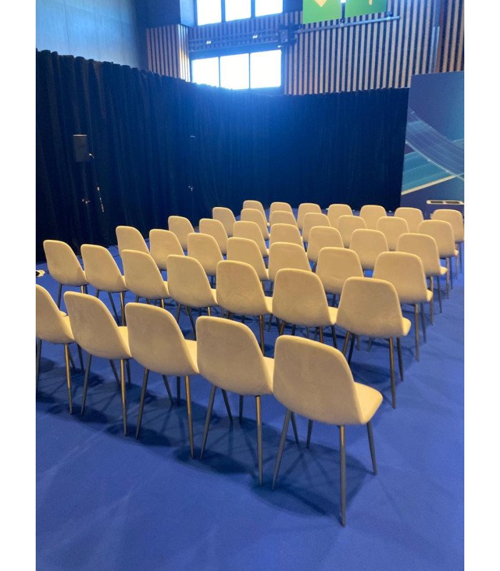 Chaises en velours beige et pieds dorés disposées en rangées dans une salle de conférence
