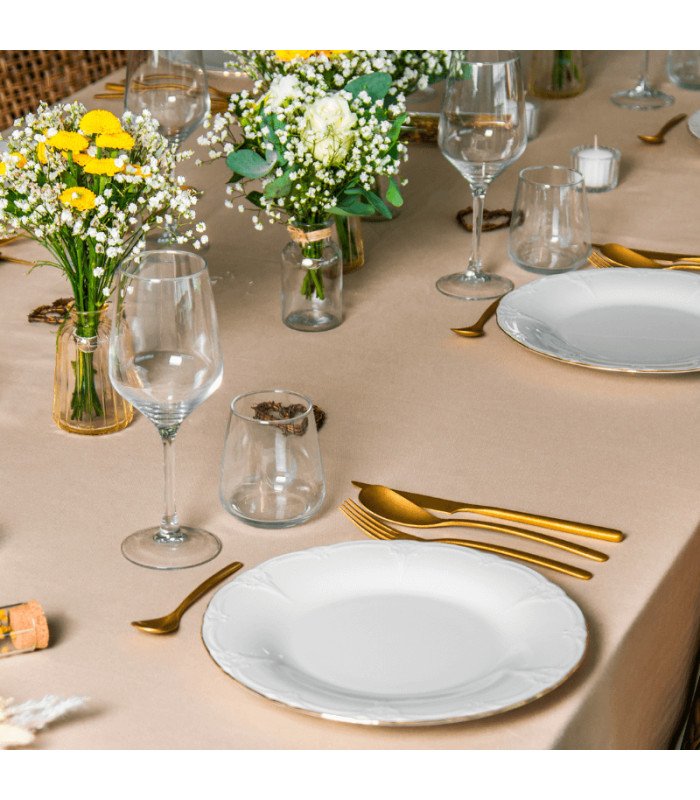 Assiette en porcelaine blanc et filet or Ø 21 cm dressée sur table avec verres, couverts et décoration florale.