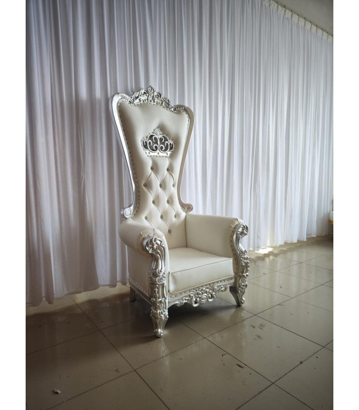 Trône de mariage argent et blanc installé en salle de réception avec rideaux blancs