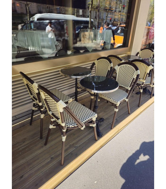 Two tables with black tops edged in silver, 50 cm in diameter, along with four bistro chairs on a Parisian terrace