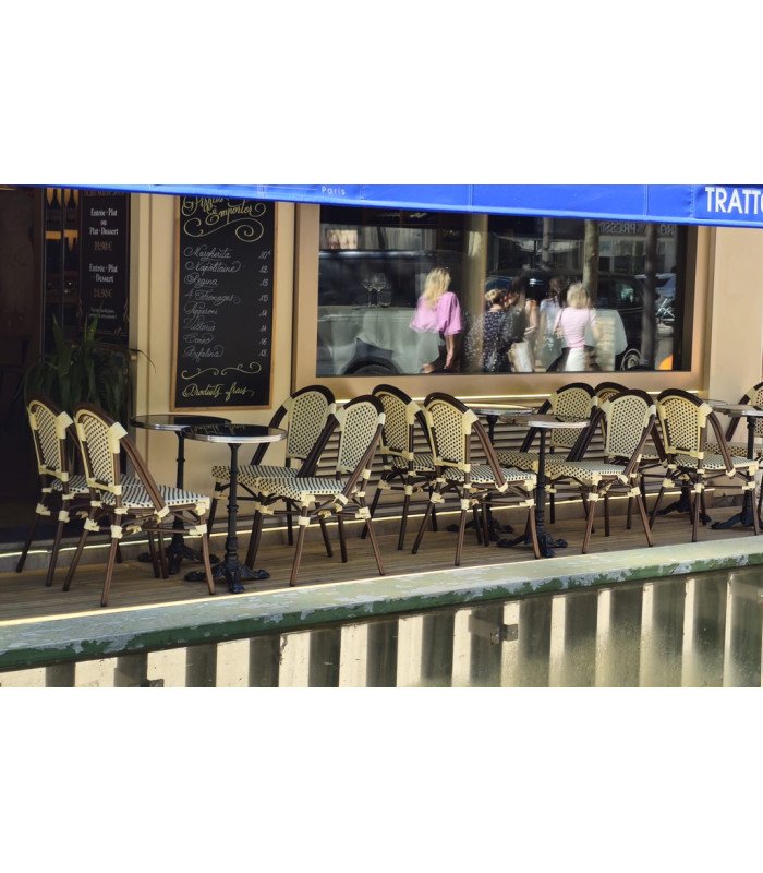 Terrasse parisienne aménagée avec tables rondes noires cerclées argent et chaises assorties