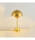 Petite lampe dorée moderne minimaliste en métal posée près d’un mur