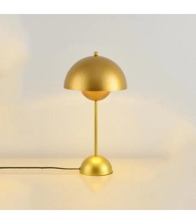 A small, modern, minimalist gold metal lamp placed near a wall